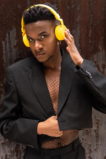 A man of black ethnicity listening to music wireless yellow headphones