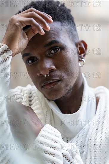 A young man of African ethnicity in a white contemporary suit and black leather boots