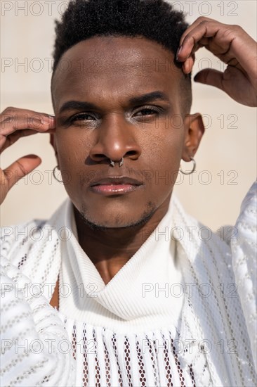 A young man of African ethnicity in a white contemporary suit and black leather boots