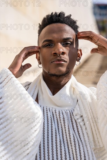 A young man of African ethnicity in a white contemporary suit and black leather boots