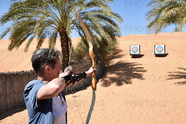 Woman doing archery in the desert of Dubai