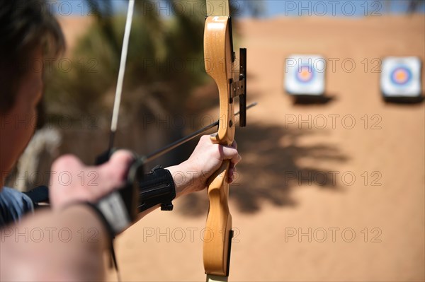 Woman doing archery in the desert of Dubai