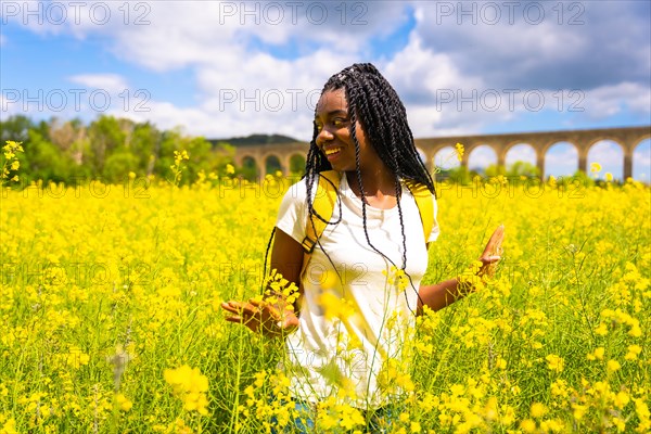 A traveler black ethnic girl with braids in a field of yellow flowers