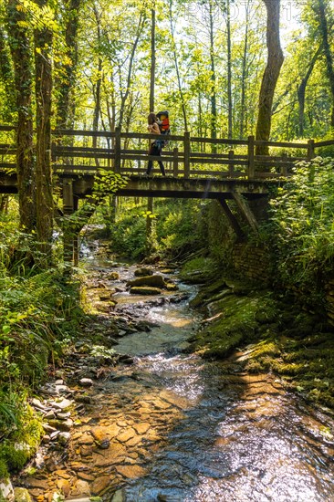 A mother with her son in her backpack crossing a wooden bridge in the Pagoeta park in Aia