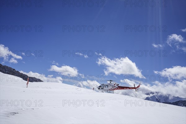 Red and white Swiss helicopter parks on Aletsch Glacier