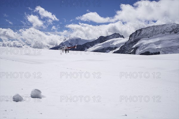 Red and white Swiss helicopter stands on Aletsch Glacier below the Jungfrau Joch