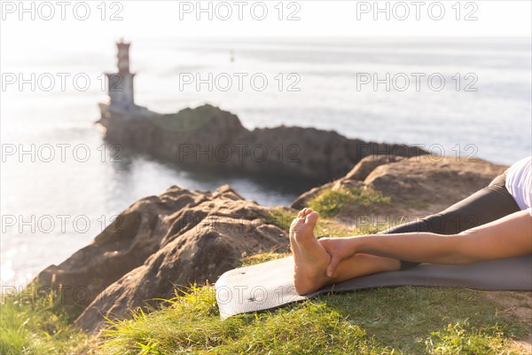 Foot of a woman doing yoga exercises in nature by the sea