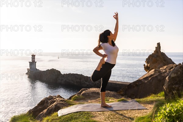 A woman performing yoga exercises in nature by the sea