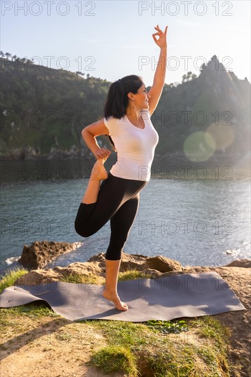 A woman performing yoga exercises in nature by the sea