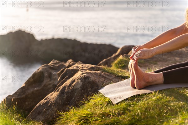 Feet of a woman doing yoga exercises in nature by the sea