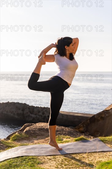 A woman performing yoga exercises in nature by the sea