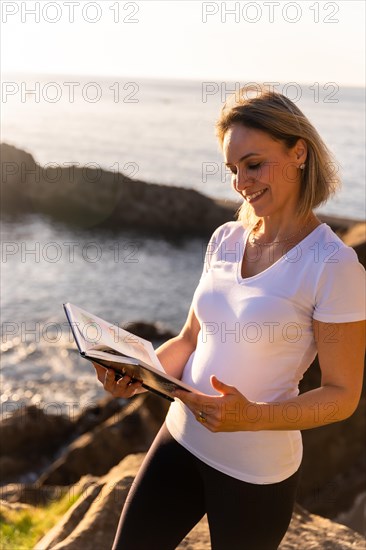 A woman reading a naturist book by the sea at sunset