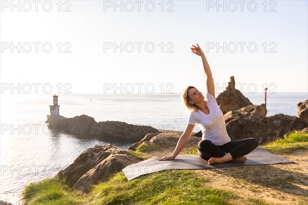 A blonde woman doing yoga exercises in nature by the sea