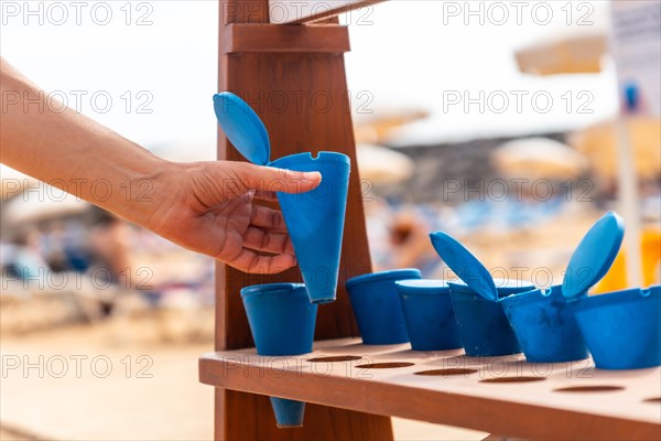 A woman taking an ashtray to smoke on the beach in summer and not throw the ash or the cigarette on the sand