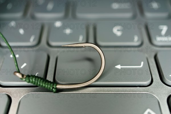 Close-up of a fishhook on a computer keyboard phishing concept