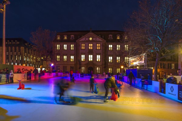 Skaters on a colourfully illuminated artificial ice rink