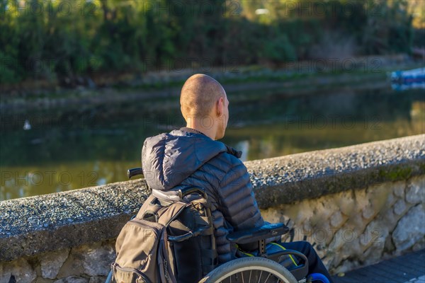 A disabled person in a wheelchair in a park at sunset next to a river
