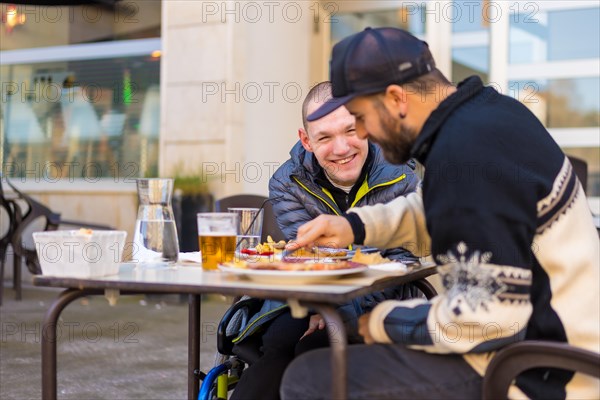 A disabled person eating and smiling with a friend having fun