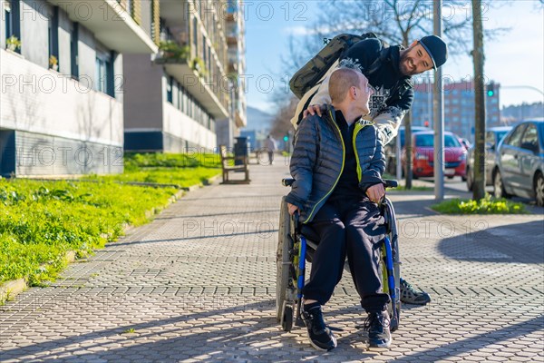 A disabled person in a wheelchair walking with a friend in a chair on the street in winter
