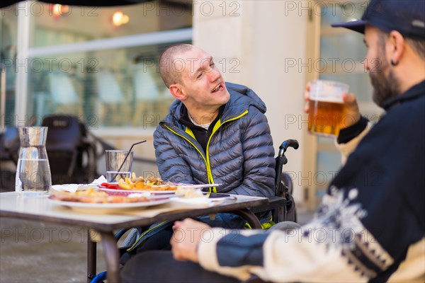 A disabled person eating and smiling with a friend having fun