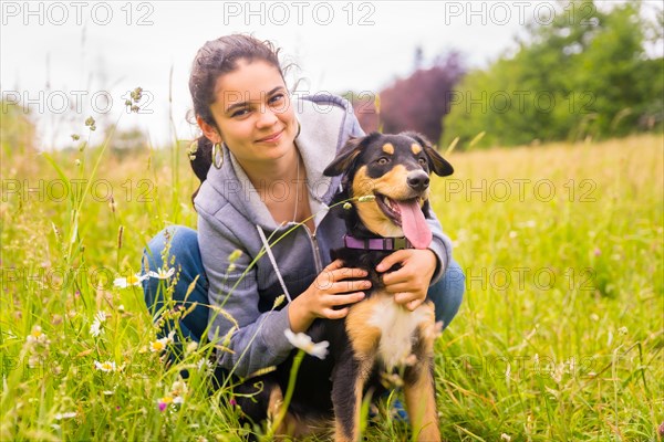 Portrait of a young girl with a cute dog sitting on a sunny spring day in a flower meadow