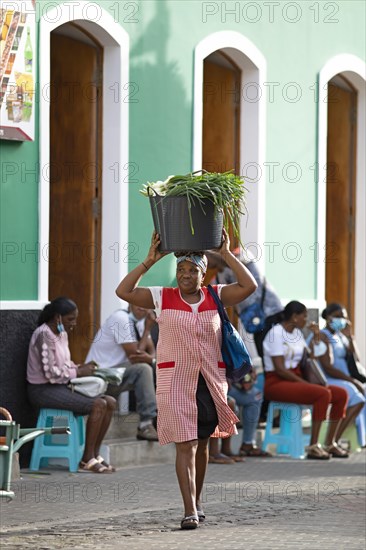 Local woman carrying spring onions in a bucket on her head