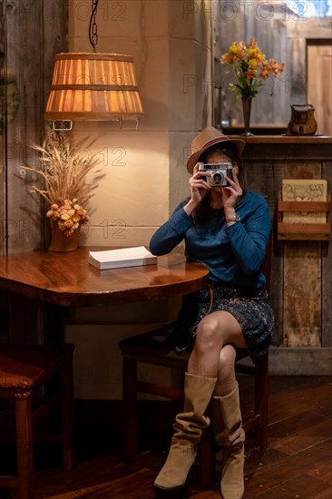 A pretty tourist with a hat and a photo camera drinking tea in a cafe