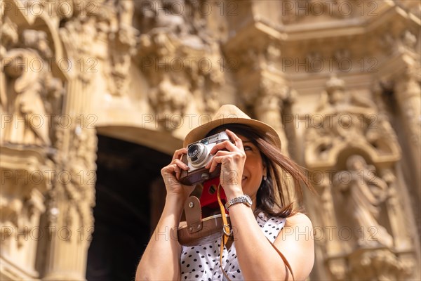 Pretty tourist in hat visiting church with photo camera