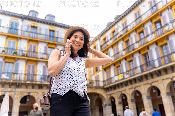 A woman in a hat visiting the city and talking on the phone