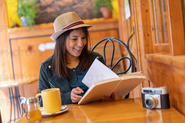 A tourist girl with a photo camera drinking tea on a cafeteria terrace