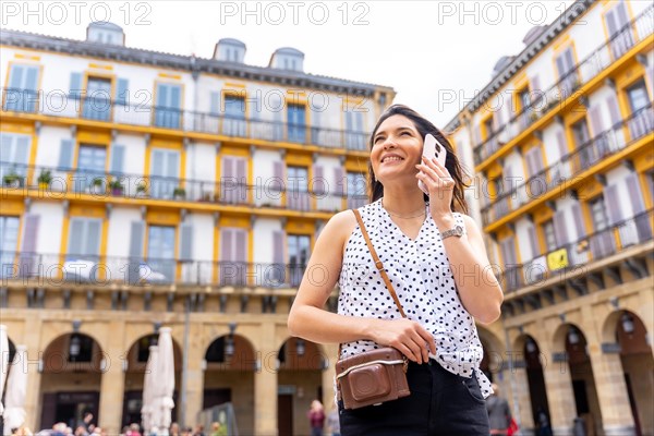 A woman in a hat visiting the city and talking on the phone