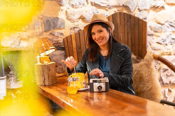 A pretty tourist with a hat and a photo camera having a cup of tea in a cafe