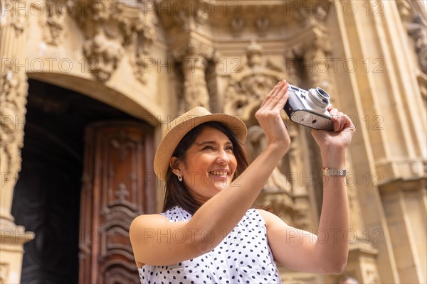 Tourist woman smiling with hat visiting a church and taking photos with a camera