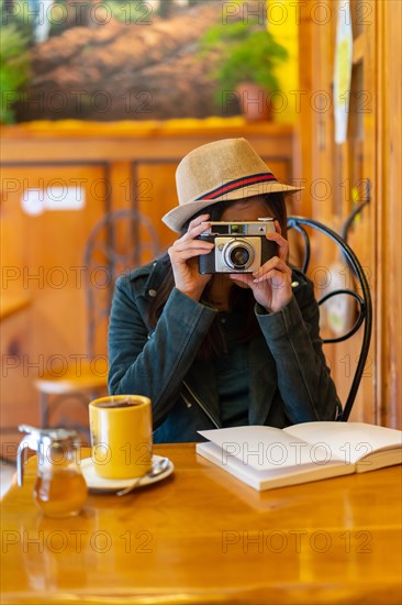 A tourist girl with a photo camera having a tea in a cafeteria terrace