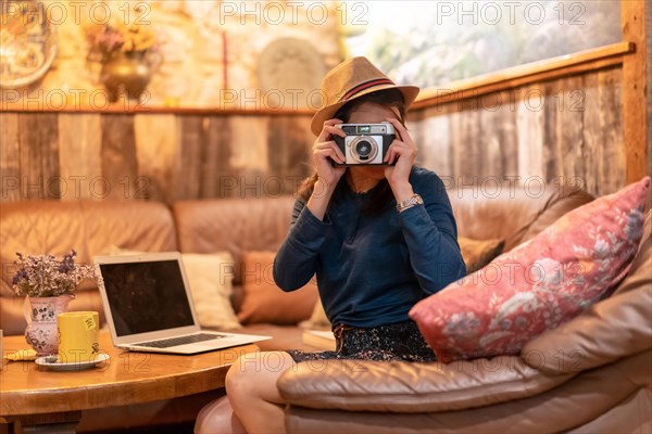 A pretty tourist with a hat and a photo camera having a cup of tea in a cafe