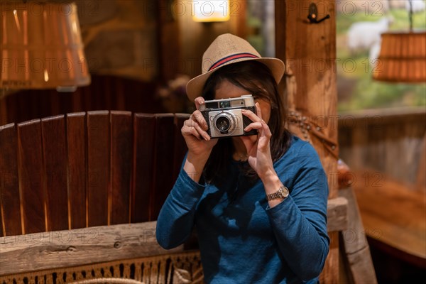 A pretty tourist with a hat and a photo camera drinking tea in a cafe