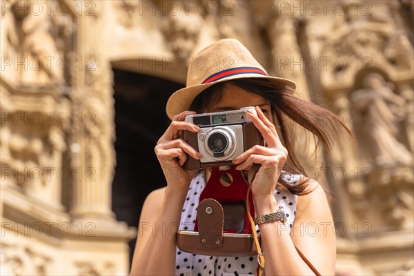 Pretty tourist in hat visiting church with photo camera