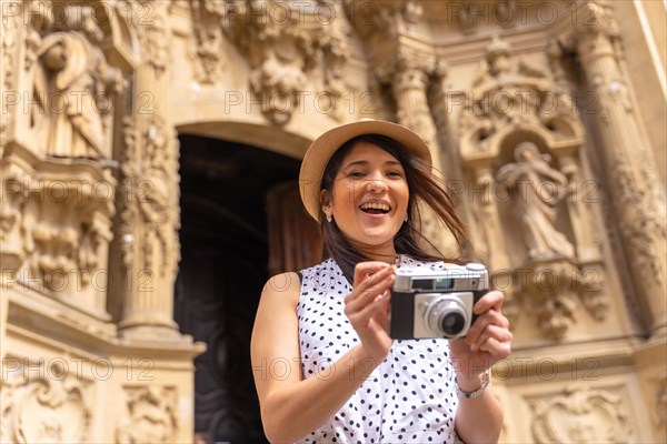 Tourist woman smiling with hat visiting a church and taking photos with a camera
