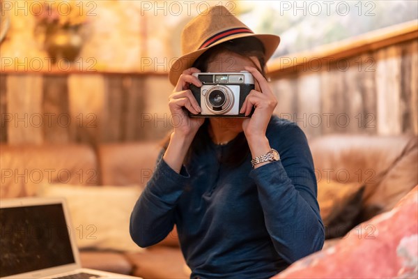 A pretty tourist with a hat and a photo camera having a cup of tea in a cafe