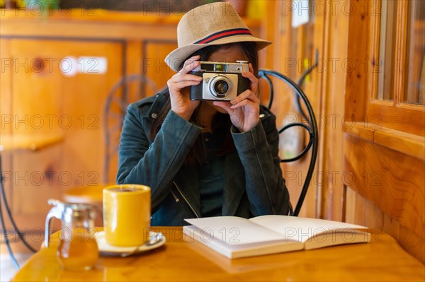 A tourist girl with a photo camera having a tea in a cafeteria terrace