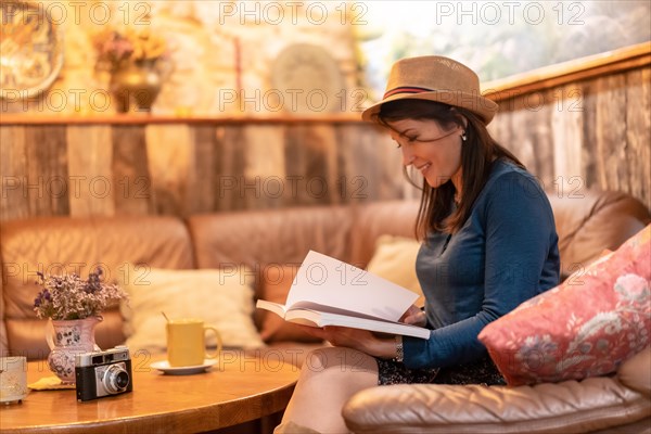 A pretty tourist with a hat and with a photo camera drinking tea in a cafe
