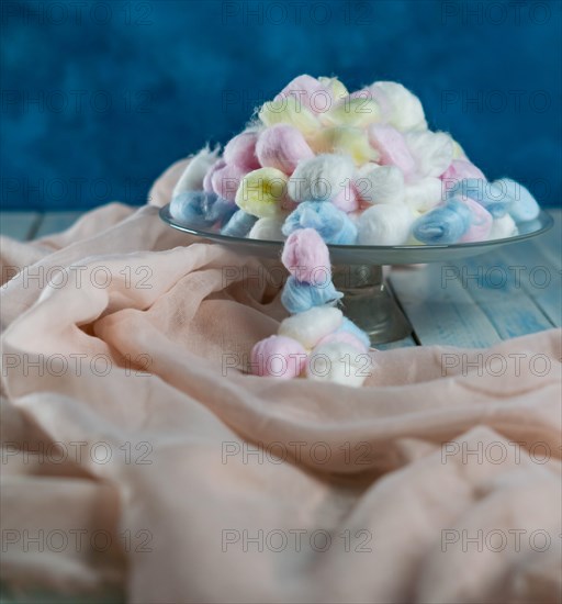 Colored cotton balls in various containers on a blue background