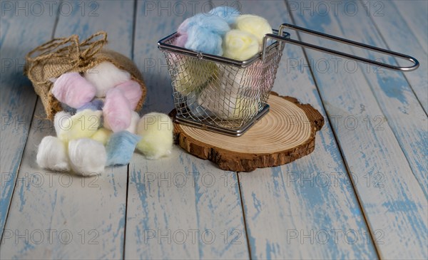 Colored cotton balls in various containers on a blue background