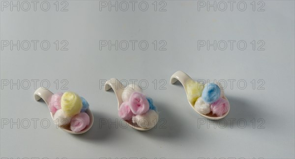 Colored cotton balls in various containers on a blue background