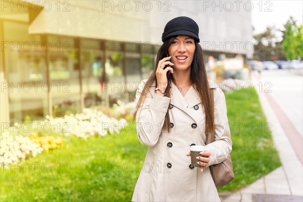 Businesswoman with a coffee in her hand and talking on the phone