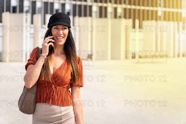 Portrait of a businesswoman outside the office in a brown shirt and a black hat