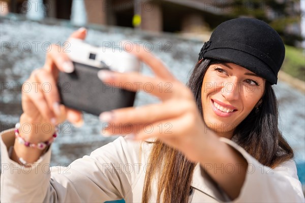 Smiling tourist woman taking a selfie with the photo camera on her summer vacation in the city