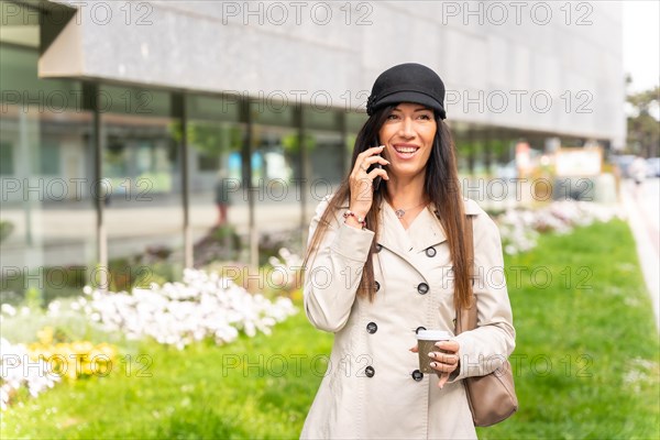 Businesswoman with a coffee in her hand and talking on the phone
