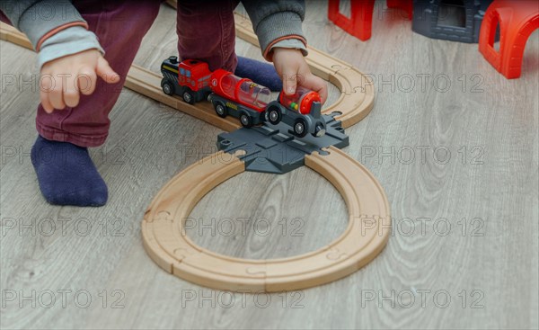 Unrecognizable child playing with a wooden train on the floor in his bedroom
