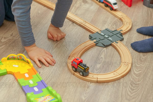 Unrecognizable child playing with his wooden train in his room